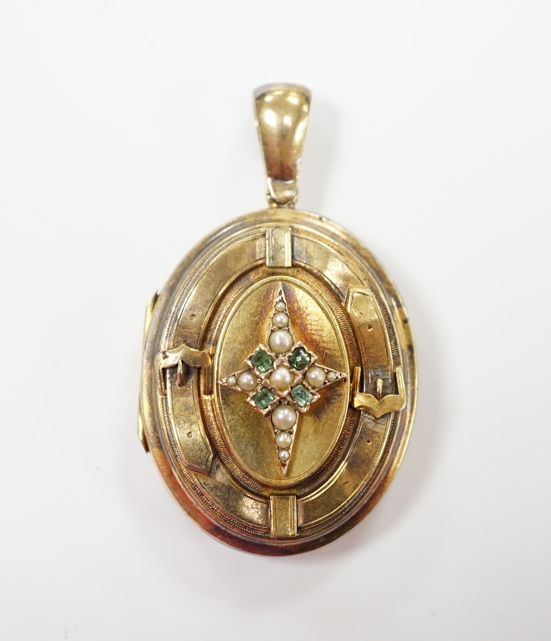 A late Victorian engraved yellow metal, seed pearl and gem set oval locket, overall 50mm, gross weight 13.5 grams.